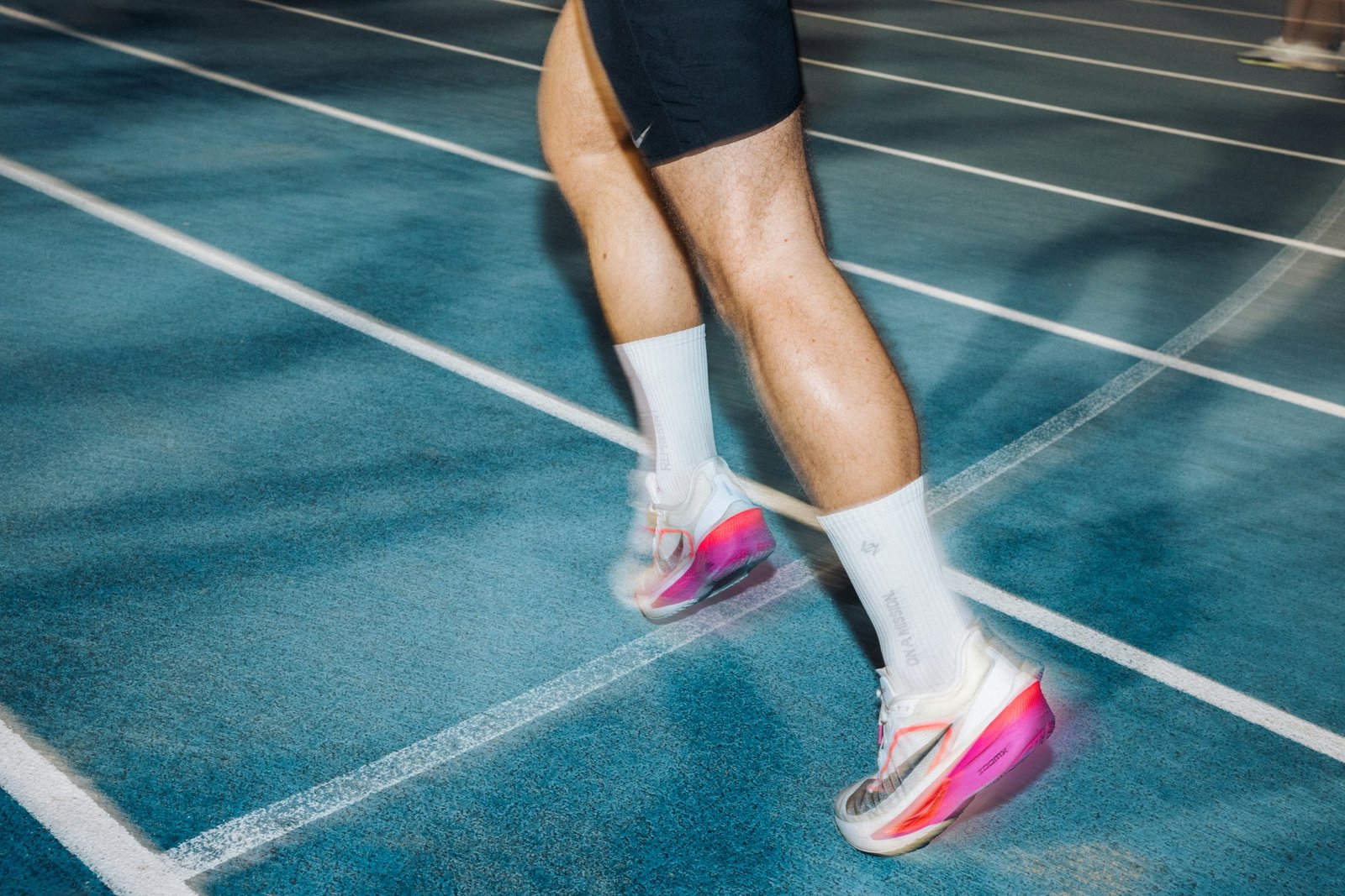 Runner's legs and running shoes in motion on a track