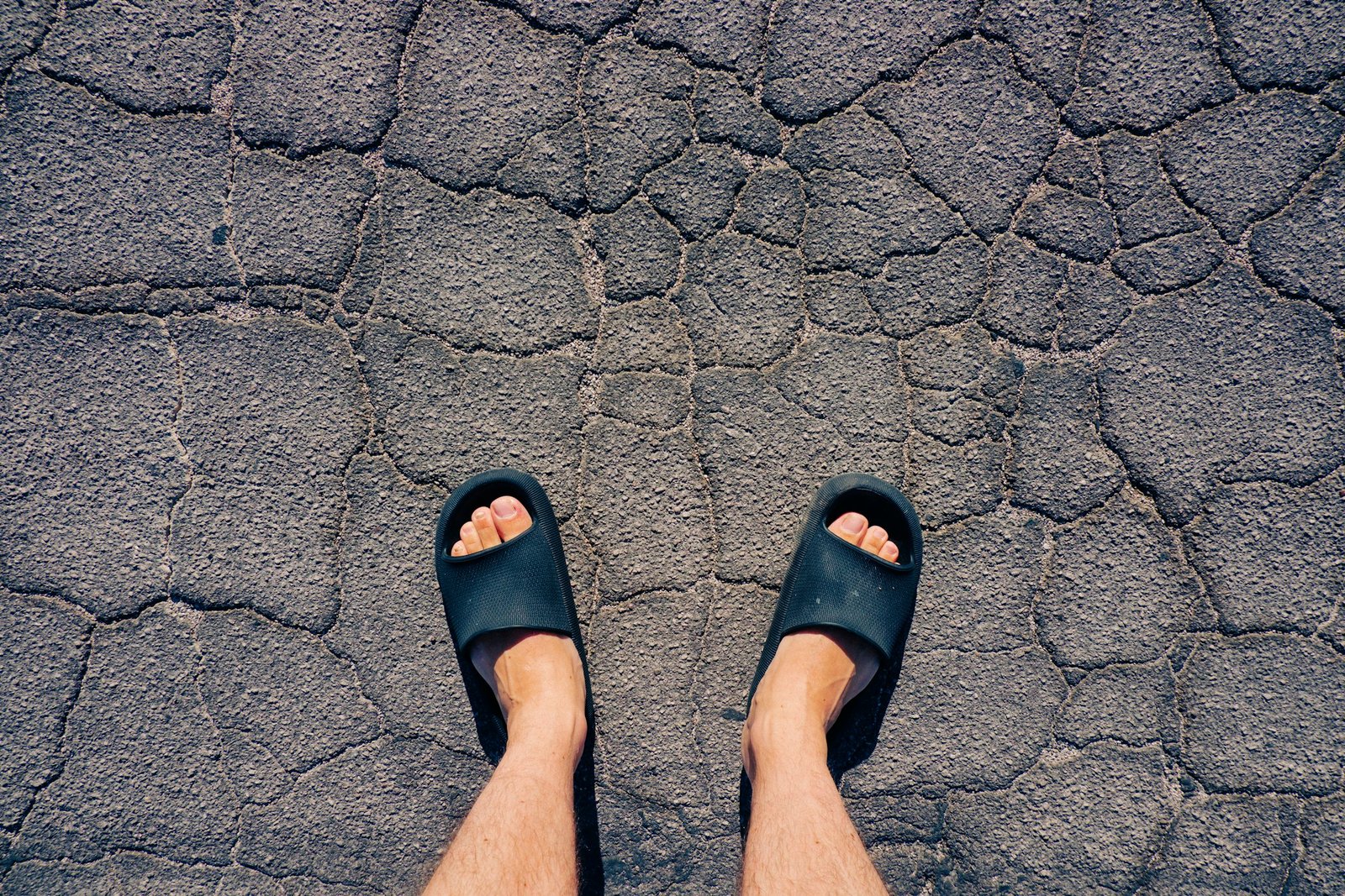 Feet in black slides on asphalt