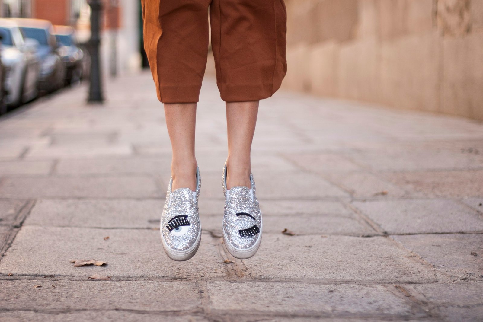 Person jumping on a city sidewalk in sneakers